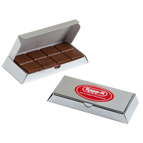 A silver box contains a milk chocolate bar with several segments inside. The box features a logo. Milk Chocolate Bar in SILVER Box - Image 1
