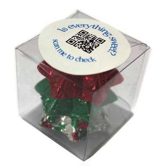 A clear cube containing Christmas-themed chocolates in red, green, and silver foil, with a circular label on top. Cube filled with Christmas Chocolates 30g - Image 1