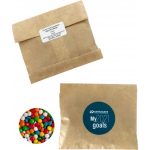 A kraft paper bag containing chewy fruit candies in vibrant colours, alongside a branded circular logo.