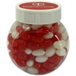 A transparent plastic jar containing red and white mini jelly beans. The jar has a white lid and a logo on top.