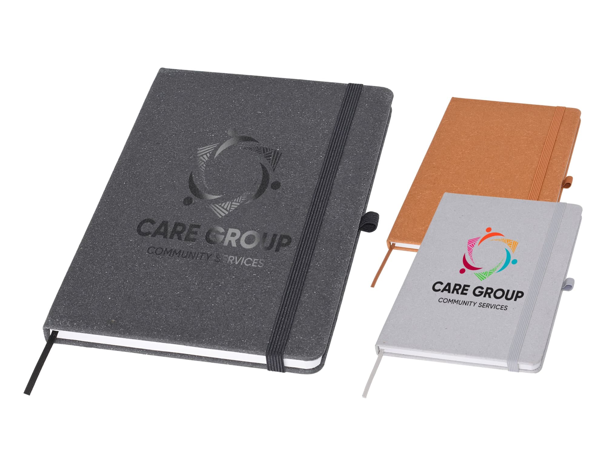 Three A5 notebooks in grey, orange, and white, featuring a logo on the covers and an elastic band closure. Toscano Recycled Notebook A5 - Image 1