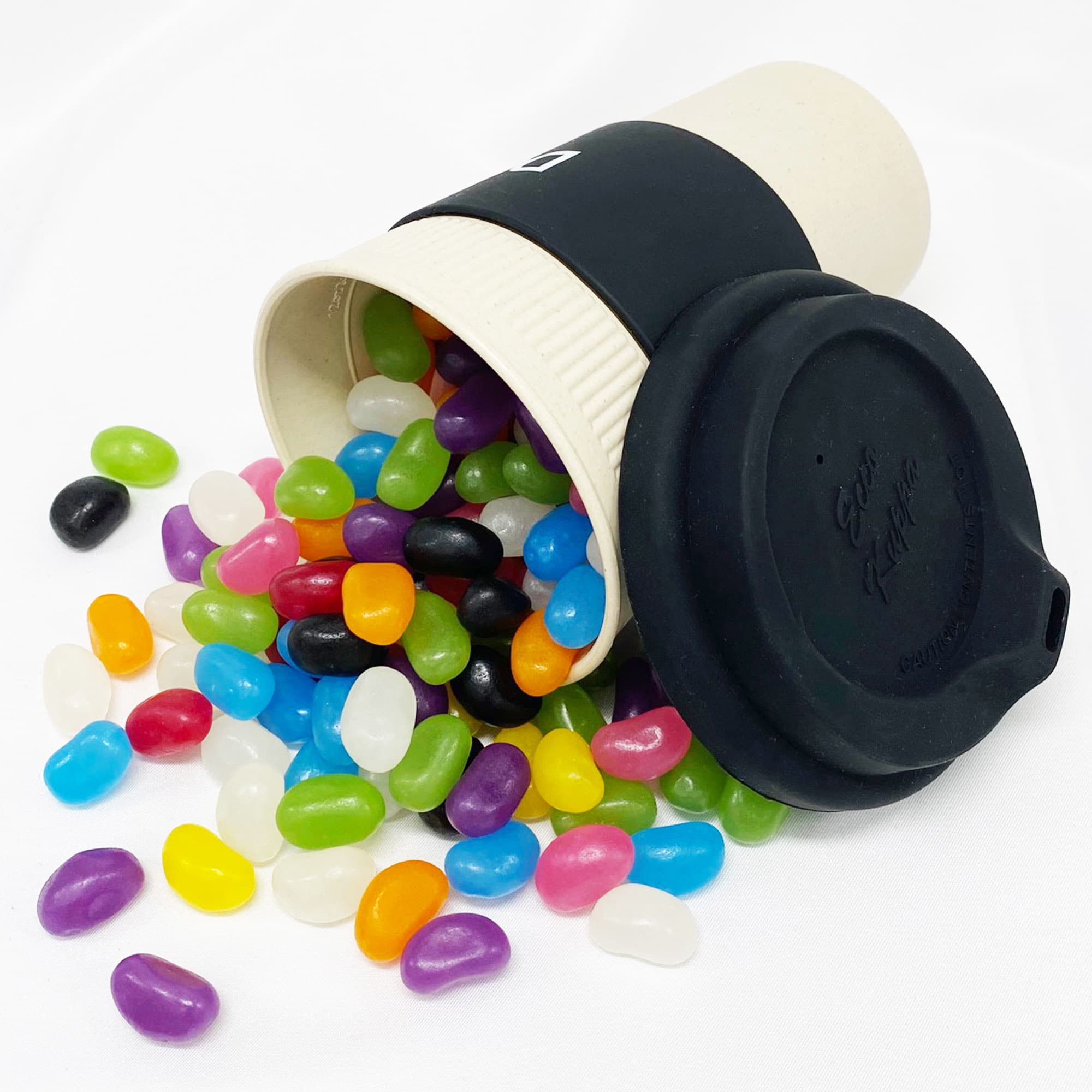 A bamboo cup in cream with a black lid, overflowing with colourful jelly beans in various hues. Jelly Bean In 12oz Bamboo Cup - Image 1