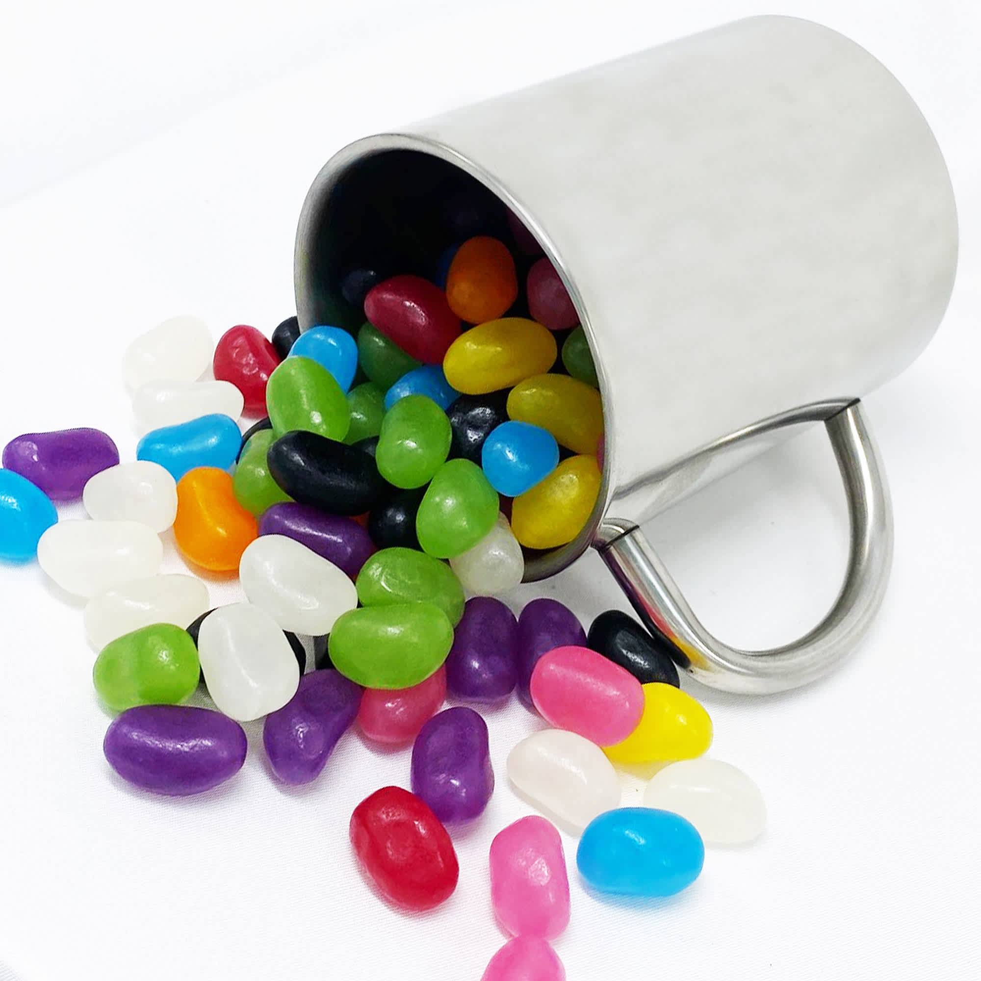 A stainless steel mug tipped over with colourful jelly beans spilling out in various shades. Jelly Bean In Alto Mug - Image 1