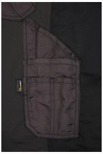 A close-up view of black workwear stretch-pants featuring multiple pockets and a branding label.