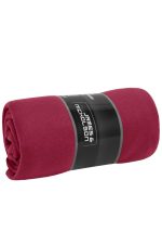 A rolled-up fleece blanket in a rich burgundy colour, featuring a logo on the packaging.