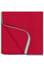 A picnic blanket in vibrant red with a grey edge. It has a soft texture and folded corners.