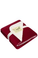 A red and cream blanket is neatly folded and secured with a ribbon, featuring a stitched edge.