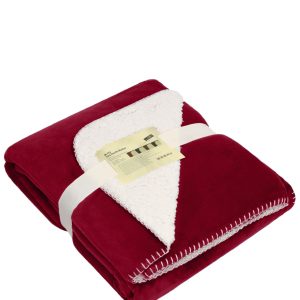 A red and cream blanket is neatly folded and secured with a ribbon, featuring a stitched edge.