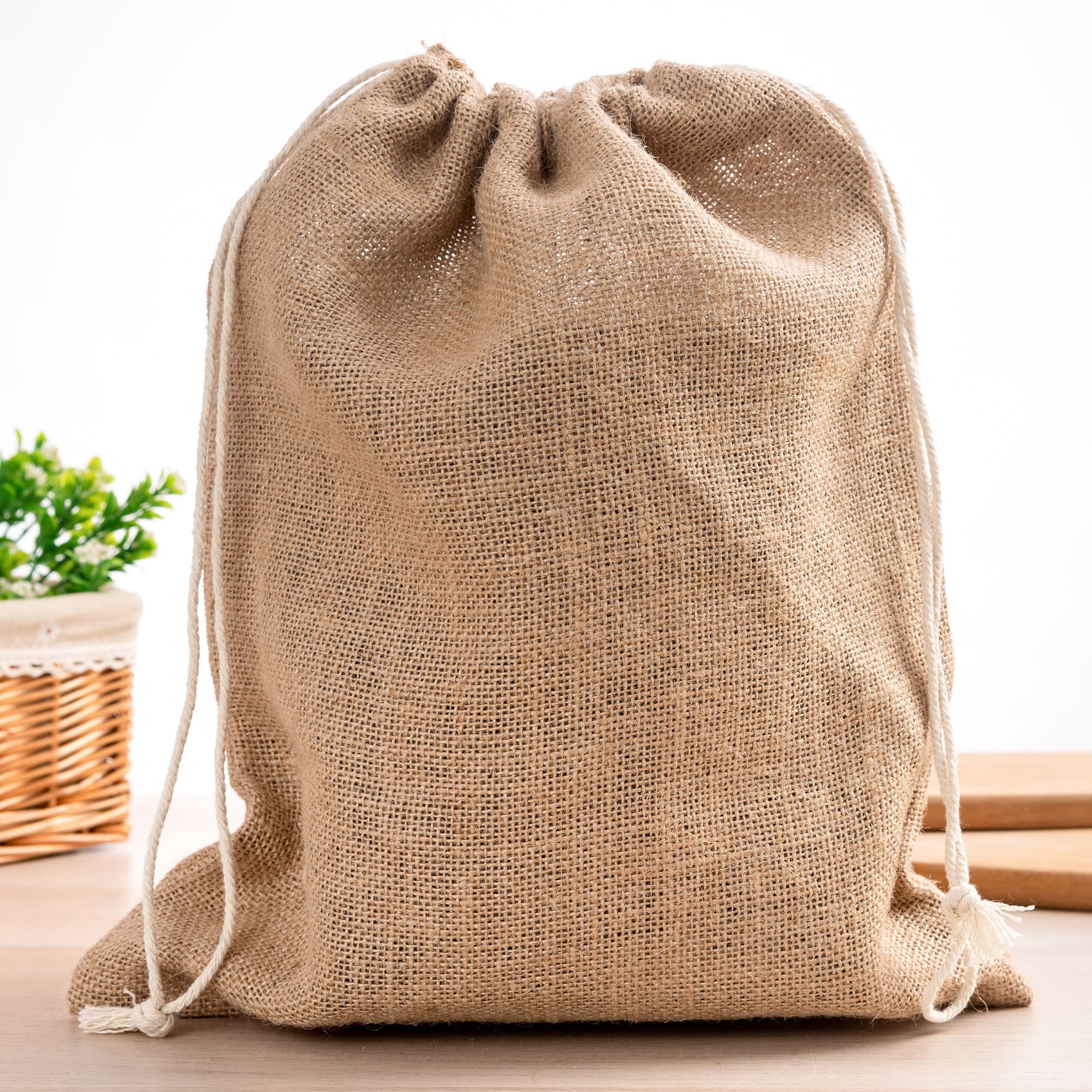 A natural beige jute bag with a drawstring closure, featuring a simple design and a logo. Maryland Produce Jute Bag - Image 1