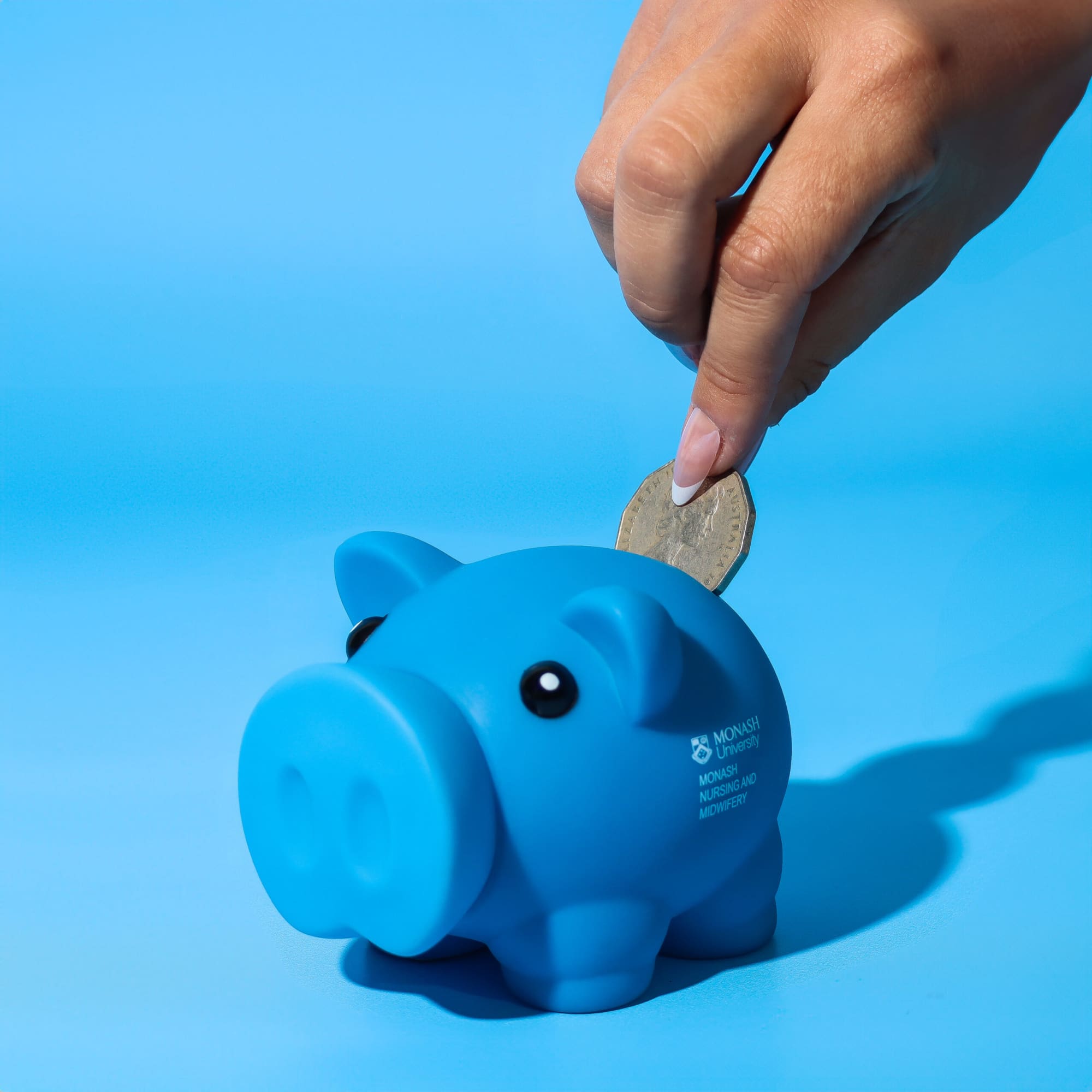 A blue piggy bank with cartoonish features, being fed a coin. It has a logo on its side. Penny Piglet - Image 1