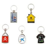 A collection of five metal key rings in various shapes and colours, each featuring a different logo or design.