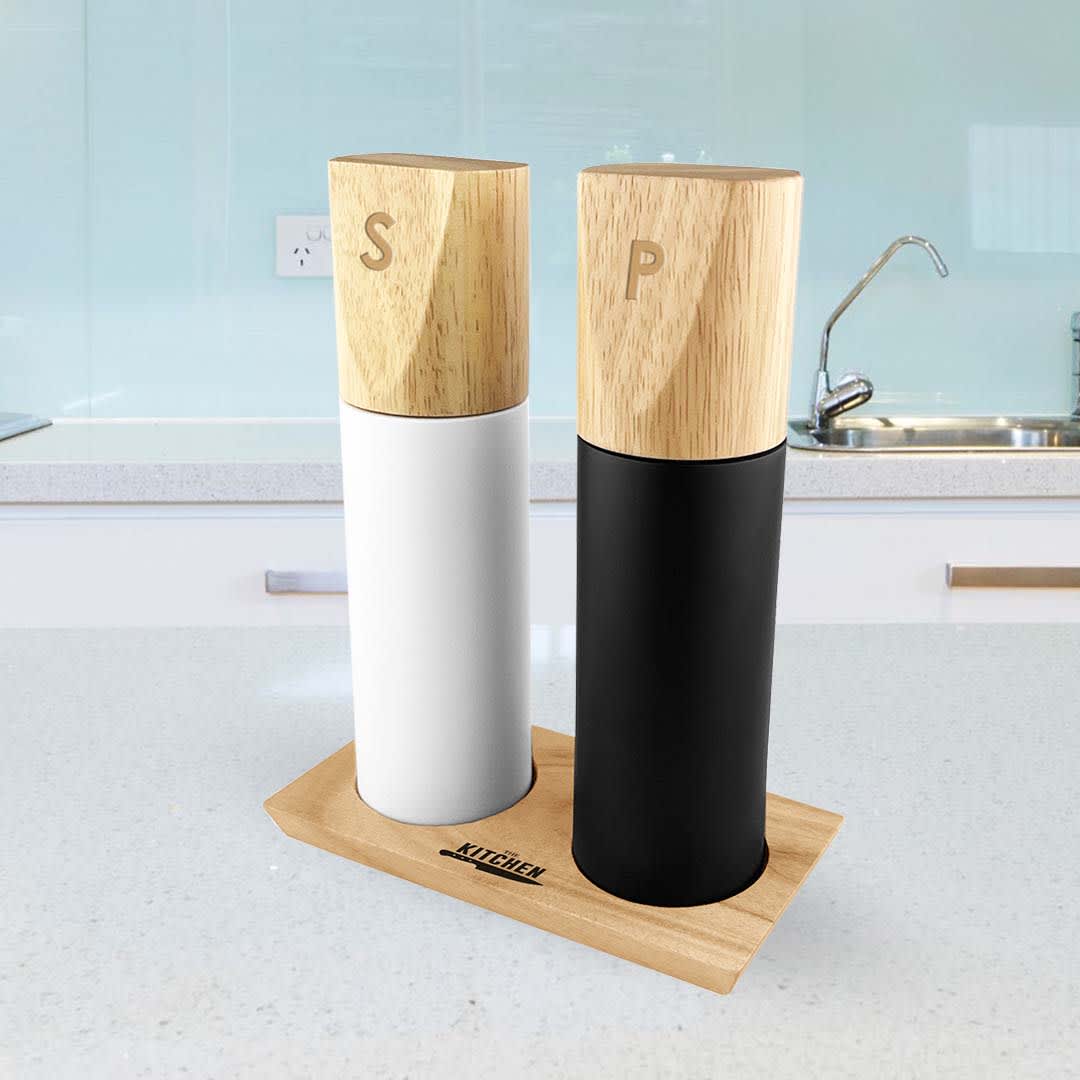 Two cylindrical grinders in white and black with wooden tops, sitting on a wooden base in a kitchen setting. Maxwell Grinder - Image 1