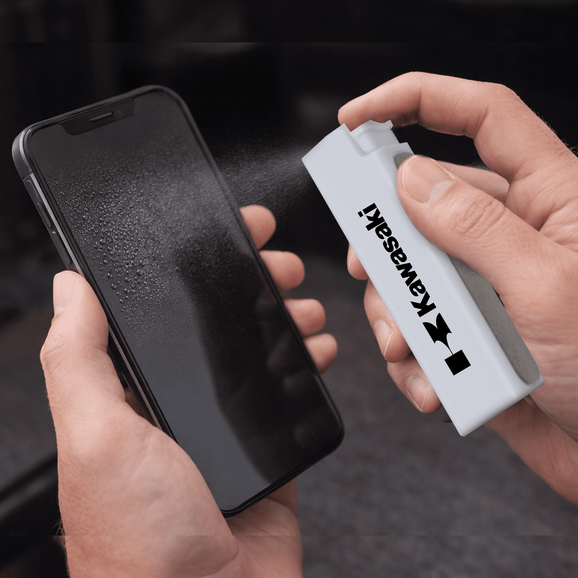 A white spray bottle is cleaning a smartphone screen, which is covered in mist. The bottle has a logo. The Wipey Screen Cleaner - Image 1