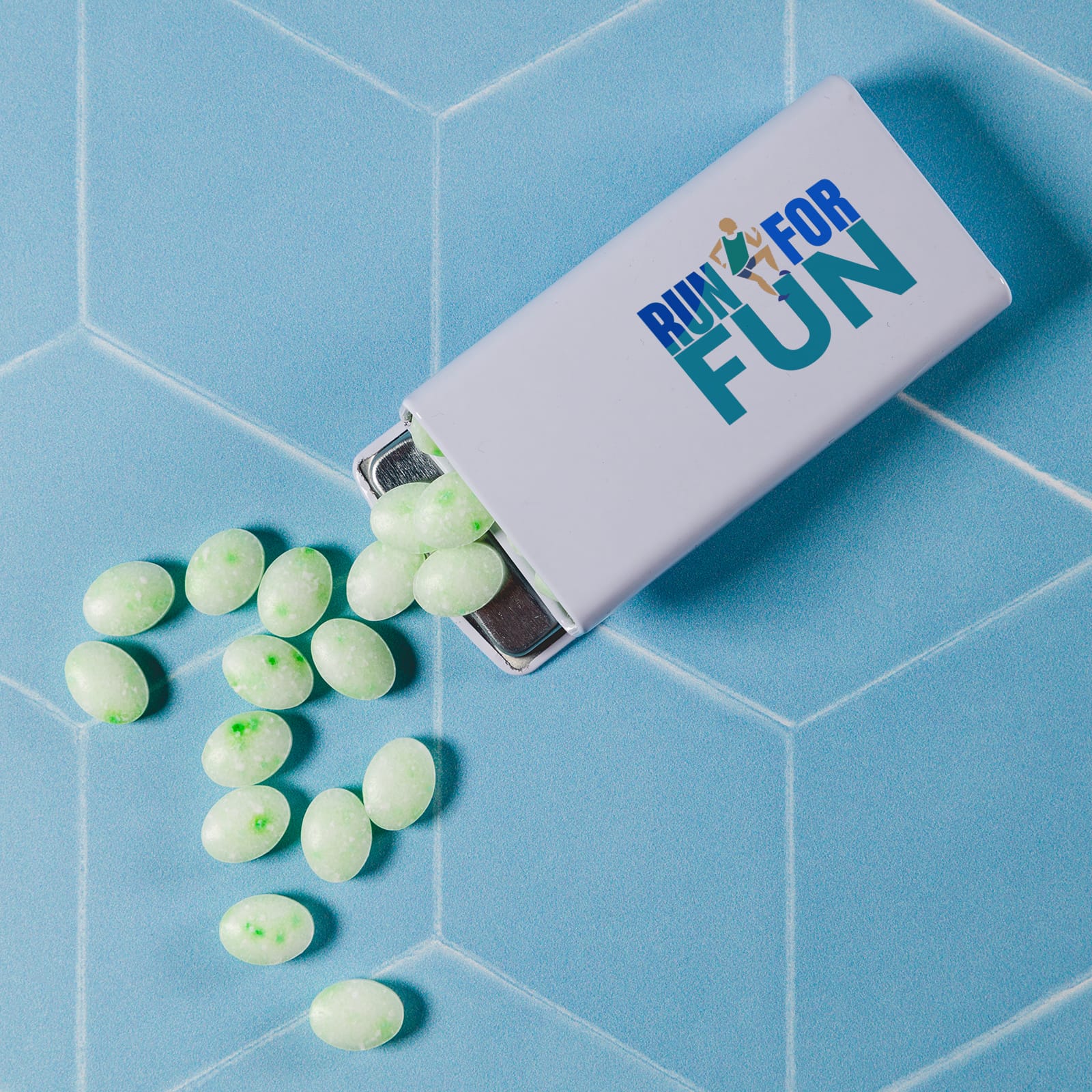 A flip top tin filled with light green spearmint mints is shown, with some mints scattered around. Spearmints in Flip Top Tin 25g - Image 1