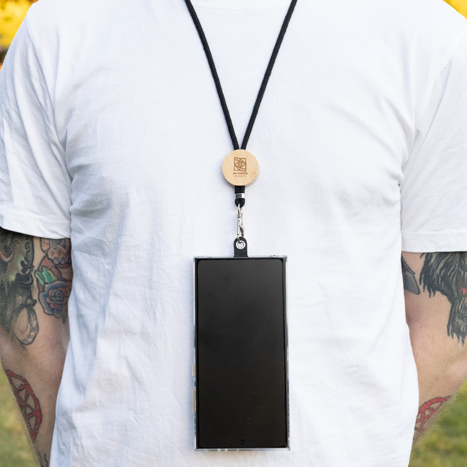 A phone neck lanyard featuring a wooden clip and a black strap, securely holding a smartphone. Shadow Phone Neck Lanyard - Image 1