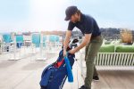 A golfer retrieves a blue golf towel from a navy golf bag, set against a sunny outdoor backdrop.