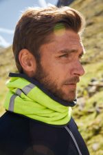 A bright yellow scarf with grey accents is worn around a man's neck against a natural backdrop.