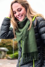 An elegant green scarf draped around a smiling woman, paired with a puffy black jacket.