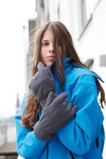A woman wearing grey Thinsulate™ fleece gloves and a blue jacket, posing outdoors.