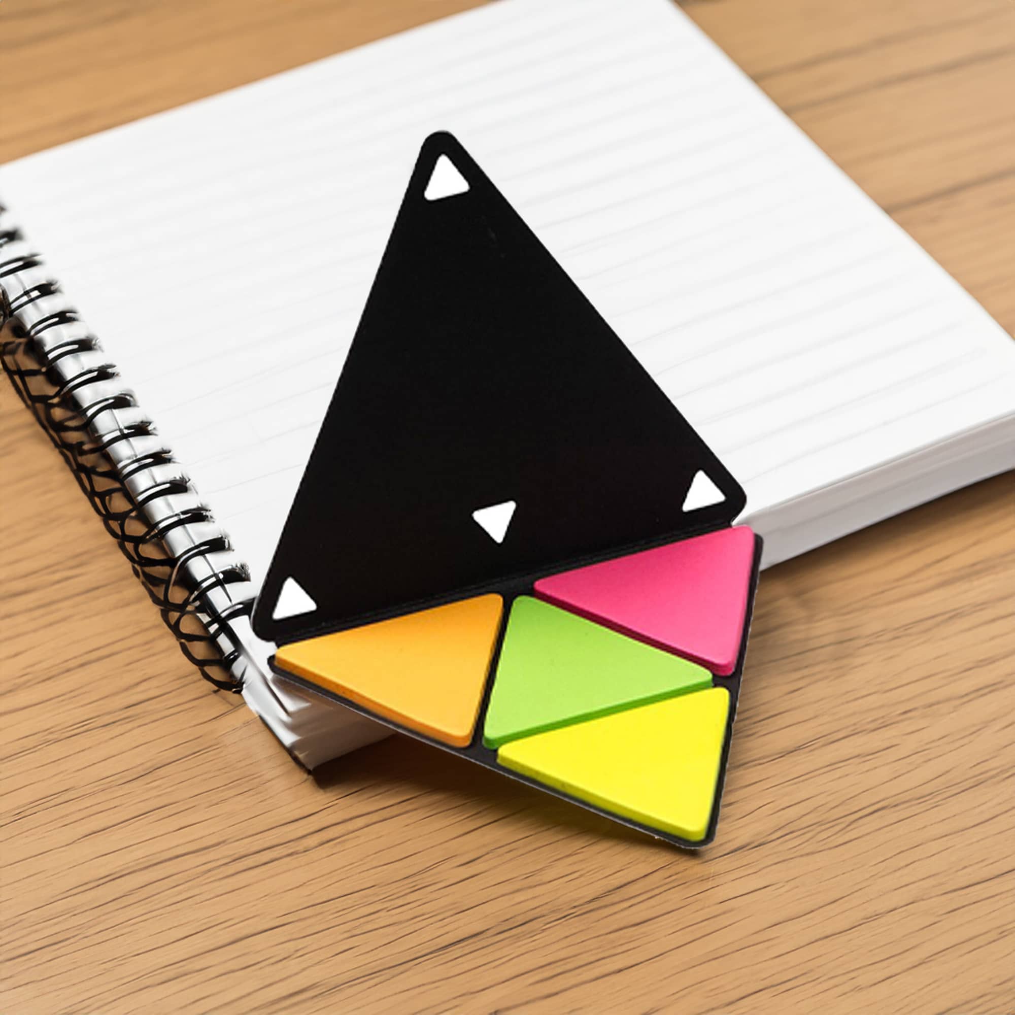 A triangular sticky note holder with black, pink, yellow, and green notes sits on a notepad with a spiral binding. Fulti Sticky Note - Image 1