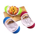 An apple cutter in blue, green, and red, placed next to a sliced apple on a wooden board.