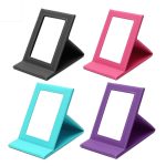 A collection of four leather-coated makeup mirrors in black, pink, teal, and purple, each with a stand and surrounding frame.