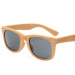 Wood-like sunglasses with grey lenses and a light wood finish. Features a logo on the side.