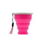 A pink collapsible silicone travel cup with a lid and a tassel attachment. It features a branding logo.