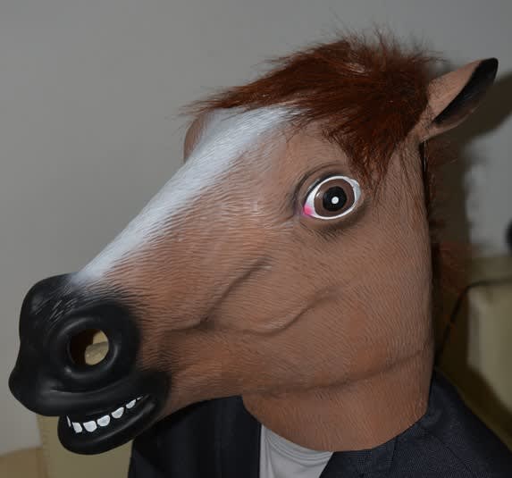 A horse mask with brown fur detail and a large open mouth feature, set against a neutral background. A horse mask with brown fur detail and a large open mouth feature, set against a neutral background.