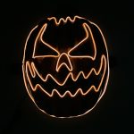 A glowing Halloween pumpkin mask with an eerie face design, featuring orange and black colours.