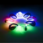A collection of LED clip-on shoe lights in various colours, arranged in a circle against a dark background.