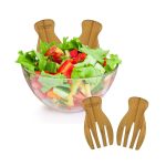 A bamboo salad serving set with two forks placed beside a clear bowl filled with fresh, vibrant salad.