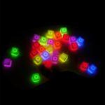 Brightly coloured light-up ice cubes in various shades of pink, green, yellow, and blue scattered against a dark background.