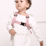 A child wearing pink anti-lost back straps, featuring adjustable clips and decorative details on the shoulders.