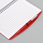 A red spiral notebook with lined pages, accompanied by a matching red pen. It features a logo on the cover.