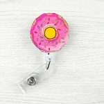 A pink donut-shaped badge holder clip with colourful sprinkles and a clear retractable cord.