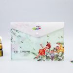 A full colour document envelope featuring a playful design with children surrounded by leaves. It has a snap button closure.