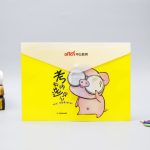 A yellow document envelope featuring a cartoon pig design and a plastic button closure, with a logo present.