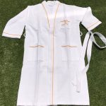 A white cotton unisex bathrobe with orange trim, featuring two front pockets and a tie belt.