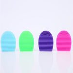 Four silicone makeup brush cleaners in blue, green, purple, and pink, featuring textured surfaces for cleaning.