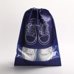 A navy drawstring bag with a clear window, featuring a design of shoes in white. Branding visible on the bag.