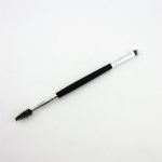 A double-headed eyebrow brush with a black handle, featuring a spoolie brush on one end and a flat brush on the other.