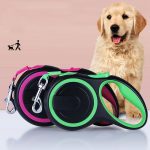 A pet telescopic leash in black with green and pink accents, alongside a golden retriever puppy. Featuring a branding logo.