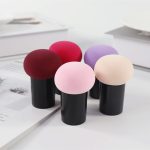 A set of five Mushroom Head Powder Puffs in colours including burgundy, pink, purple, and beige, housed in black holders.