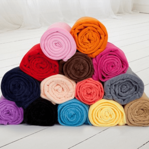 A stack of rolled flannel blankets in various colours including pink, orange, blue, and grey, with a logo visible.