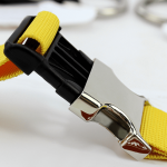 A yellow luggage belt featuring a silver buckle, designed for securing bags and luggage.