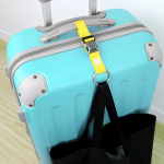 A bright yellow luggage belt secures a black bag to a turquoise suitcase, with a handle visible on top.