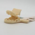 A cream-coloured baby pacifier chain holder with a clip designed to secure pacifiers.