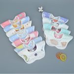 A set of colourful baby saliva towels in various pastel shades, featuring playful animal patterns and a logo.