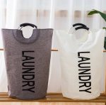 A portable laundry basket in grey and white, featuring a sturdy handle and the word "LAUNDRY" printed on the front.